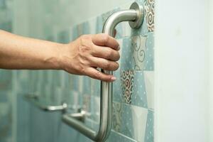 Asian elderly woman use bathroom handle security in toilet, healthy strong medical concept. photo