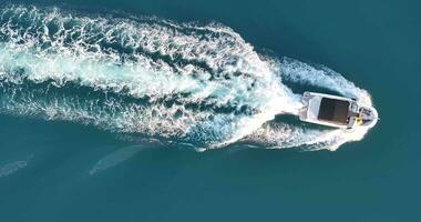 Vertical drone video on a moving yacht over turquoise water