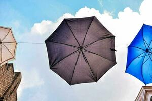 three umbrellas hanging from a line with a building in the background photo