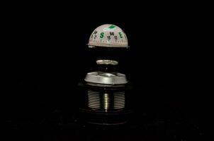 a black and silver compass on a black background photo