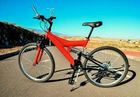 un rojo montaña bicicleta es estacionado en el lado de un la carretera foto