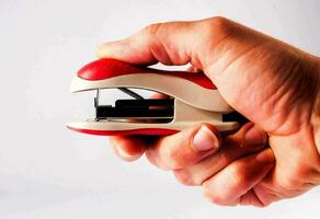 a person holding a red and white stapler photo