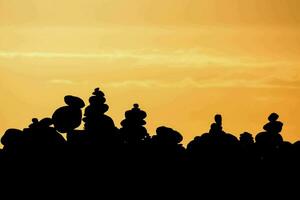 a stack of rocks is silhouetted against the sun photo