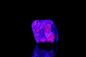 macro mineral stone ruby under ultraviolet light on a black background photo