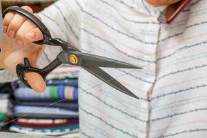 Female hands of a master tailor cuts a thread with scissors photo