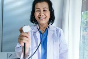 Cardiologist supports the heart senior asian woman doctor wearing glasses and uniform. portrait of mature old asian woman medic professional photo