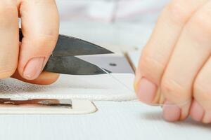 Female hands of a master tailor cuts a thread with scissors photo