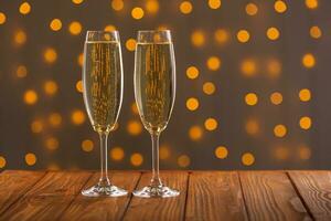 Glasses with champagne on a wooden background against a bokeh background of lights photo