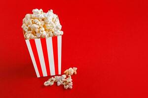 Glass with popcorn on a red background photo