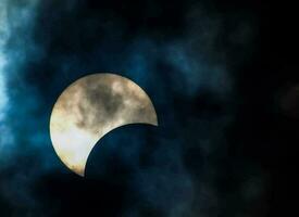 the moon is seen during a partial solar eclipse in the sky photo