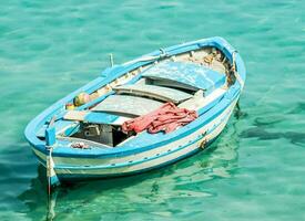 un pequeño azul barco flotante en el claro agua foto