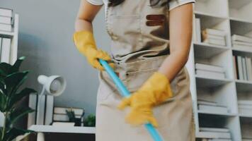 huisvrouw gebruik makend van vacuüm schoonmaakster Aan de vloer. vervelend een schort naar schoon de leven kamer Bij huis. jong vrouw is gelukkig naar schoon huis. hulp in de huishouding schoonmaak onderhoud. video