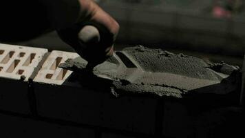 A builder lays bricks at a construction site, a close-up of the worker hands. video