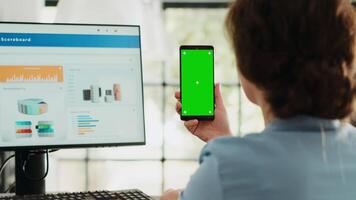 chef innehar telefon med grönskärm i företag byrå arbetsplats. affärskvinna arbetssätt med isolerat attrapp mall medan som visar tom Chromakey visa, börja jobb uppgifter. video