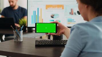 arbeider onderzoekt leeg mockup lay-out Aan modieus mobiele telefoon met groene scherm Scherm. werken Aan smartphone en computer Bij agentschap kantoor bureau, analyseren mobiel software met blanco Chroma sleutel. video