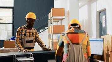 African american employees doing fist bump gesture in warehouse, greeting each other at work. Team of men working in storage room with containers and boxes of merchandise. Handheld shot. photo