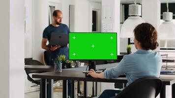 Employee using computer at desk, monitor running greenscreen template in business agency office. Company specialist looking at isolated chromakey display with mockup copyspace, digital network. video