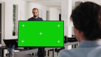 Office manager uses greenscreen on pc and working with isolated monitor display for business development. Woman looking at computer showing blank chromakey layout on desk. Handheld shot. video