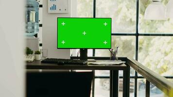Modern coworking space with monitor showing isolated greenscreen, blank chromakey screen on computer. Empty office desk with pc running mockup template, copyspace layout on desktop. video