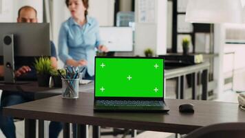 grönskärm bärbar dator i coworking Plats placerad på tömma kontor skrivbord, öppen golv planen företag arbetsplats med isolerat visa. bärbar dator löpning tom Chromakey layout på programvara. video