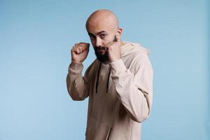 Young arab man standing in aggressive pose with clenched fists, ready to fight portrait. Angry fighter making boxing gesture, preparing for attack while looking at camera photo