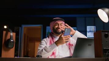 arabo uomo controllo su su vicino amico durante video conferenza incontro al di sopra di il Internet. mezzo orientale persona godendo tempo insieme con amico nel in linea video chiamata sessione mentre a casa