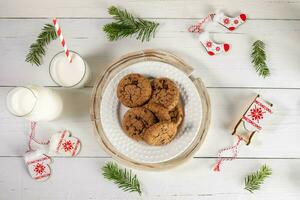 Milk, cookies, Christmas symbols, fir twigs on white wooden table. Milk for Santa Top view flat lay photo
