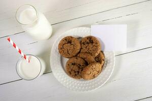 leche, galletas, vacío Nota en blanco de madera mesa. Navidad tradicion - Leche para Papa Noel. parte superior vista. foto