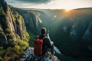 Man with a backpack on the edge of a cliff against the background of the setting sun, Man sitting on cliff edge alone enjoying aerial view backpacking lifestyle travel adventure outdoor, AI Generated photo