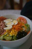 Delicious and fresh mixed salad with tuna, tomato, hard-boiled eggs, lettuce, sweet corn, grated carrot and black olives. photo