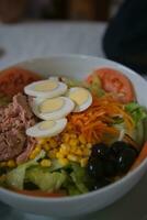 Delicious and fresh mixed salad with tuna, tomato, hard-boiled eggs, lettuce, sweet corn, grated carrot and black olives. photo