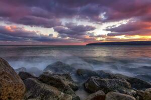 Amazing view after sunset at the rocky shore with motion blur water photo