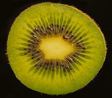 cerca arriba de corte en medio de kiwi Fruta disparar en contra un negro antecedentes. foto