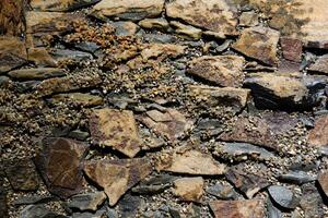 Stone background, rock wall backdrop with rough texture. Abstract textured surface of stone material. Nature detail of rocks. photo