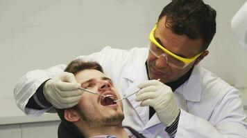 proche en haut de une professionnel dentiste examiner les dents de le sien patient video