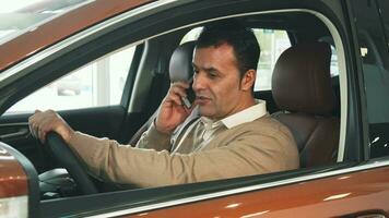 le heureux homme séance dans le voiture et parlant sur le téléphone video