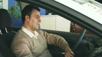 A careful man is studying the steering wheel of the car and the buttons inside the salon video