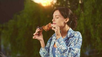 joven mujer comiendo A la parrilla carne a patio interior. disfrutando parilla, soleado día al aire libre en naturaleza. video