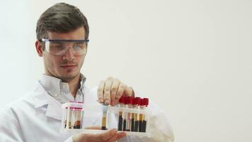 The doctor wearing special laboratory glasses examines test tubes with blood video