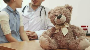 pendant le accueil de le fille à le médecin, sur le table est assis une petit nounours ours video