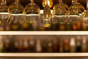 Clean wine glasses hanging over the bar counter on out of focus background photo