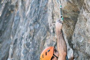 Close-up from above, rock climbing using outdoor safety harness and helmet. photo