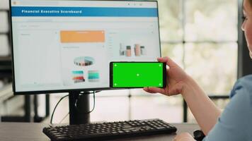 zakenvrouw analyseren smartphone app met groene scherm sjabloon in opstarten coworking ruimte. persoon op zoek Bij geïsoleerd Chroma sleutel Scherm met mockup Aan digitaal mobiel apparaat, kopieerruimte. video