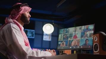 Arab man paying attention in webinar internet teleconference classroom. Muslim student in online videocall with tutor and other diverse multiethnic colleagues, listening to lesson video