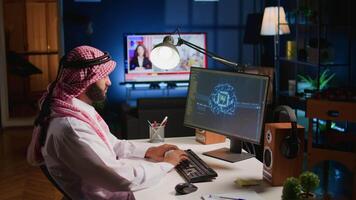 Trained arabic technician updating neural networks, writing intricate binary code scripts on computer. Middle Eastern man uses digital device programming to upgrade AI with TV as background noise video