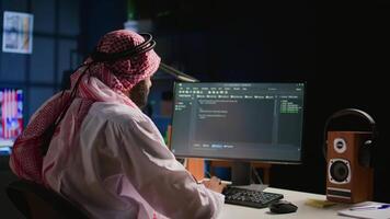 Trained muslim engineer writing code on computer screen while in office using Java programming languages. Middle Eastern developer working on fixing database errors while working from personal office video