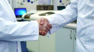 Two men shake hands at the laboratory video