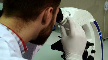 homme tourne grossier ajustement bouton sur microscope à le laboratoire video