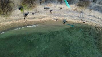 aéreo ver de personas baños en el sol, nadar, y jugando juegos en el playa. parte superior ver desde zumbido a playa y azur mar video