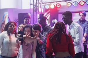 sonriente novias tomando selfie en teléfono inteligente mientras ir de fiesta con amigos en Club nocturno. alegre mujer posando para móvil teléfono foto mientras teniendo divertido a discoteca en club